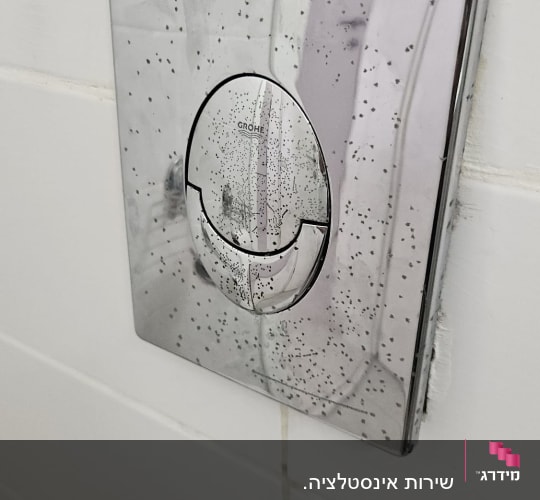לחצן הפעלה כרום לניאגרה סמויה מתוצרת Grohe על קיר אריחים לבנים